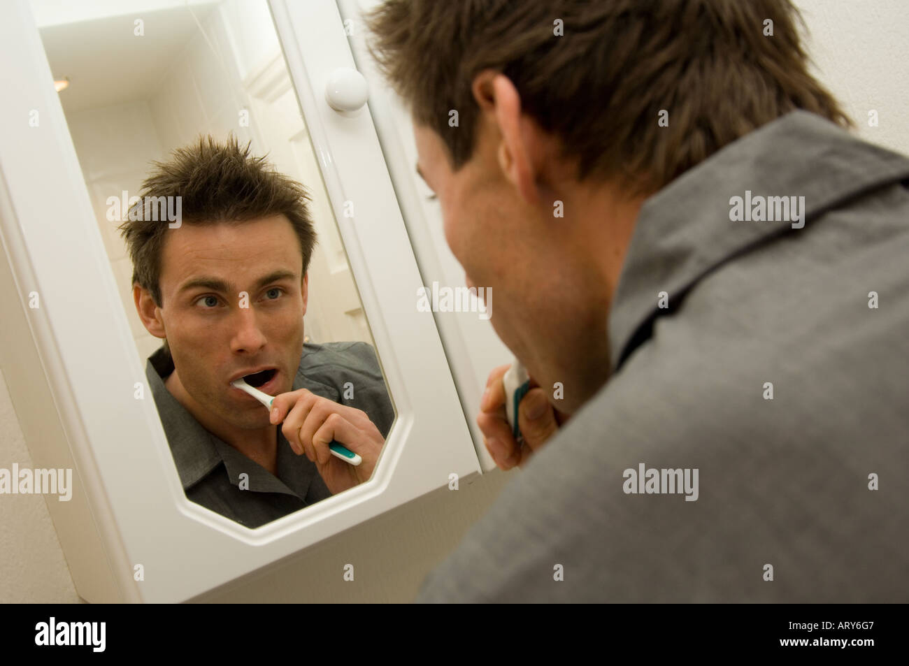 man looking into a bathroom mirror and brushing teeth Stock Photo Alamy