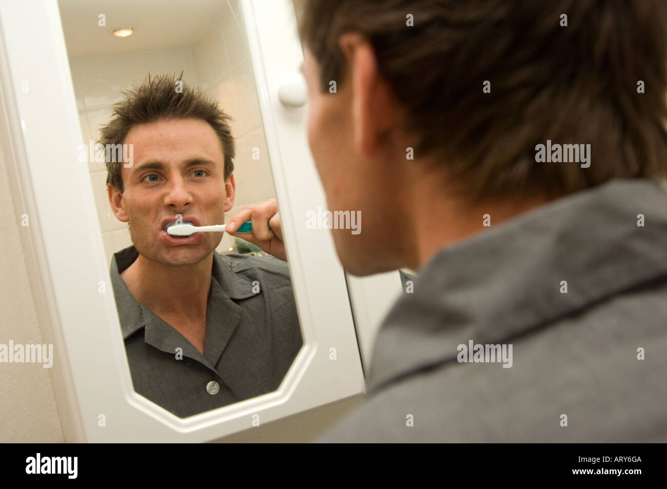 man looking into a bathroom mirror and brushing teeth Stock Photo Alamy