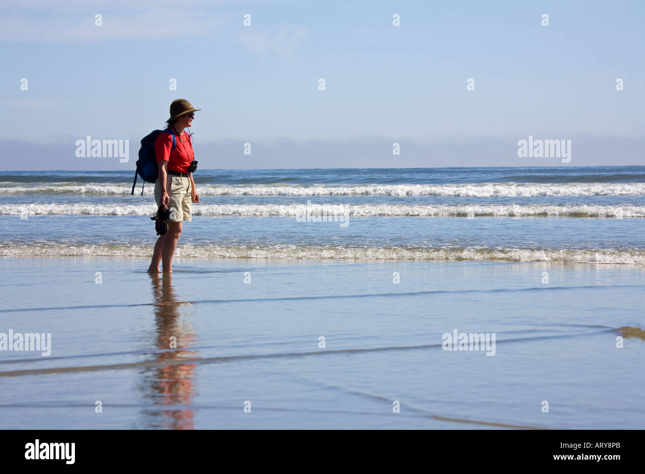 Woman walking on beach carrying sandals Long Beach Pacific Rim national park reserve Vancouver island Canada Stock Photo