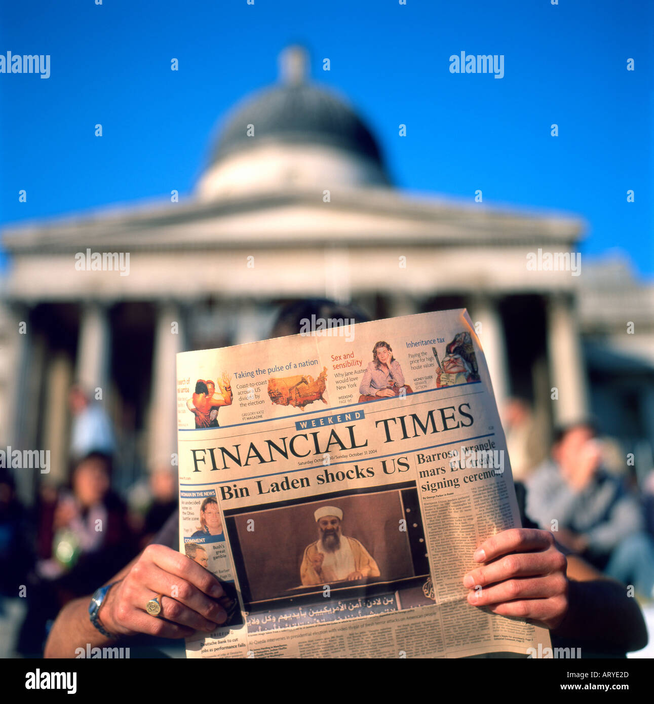 Person reading Financial Times newspaper  with Osama Bin Laden headline  'Bin Laden Shocks US'  outside the National Gallery in London UK October 2004 Stock Photo