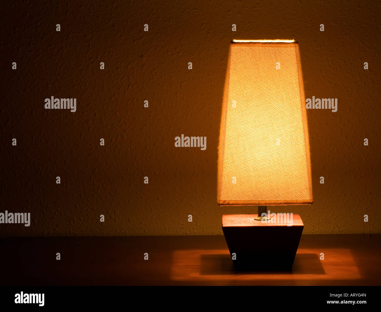 Lit bedside lamp over nightstand Stock Photo