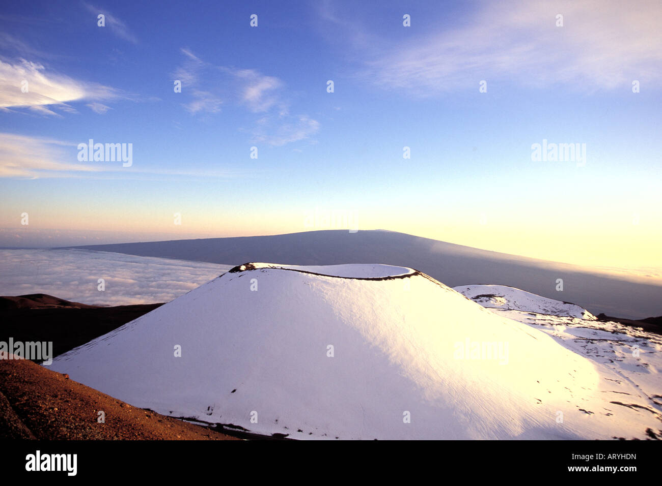 Snowcapped Puu Lilinoe (crater) at 12,987 feet elevation, just below the summit of Mauna Kea, with Mauna Loa in the background Stock Photo