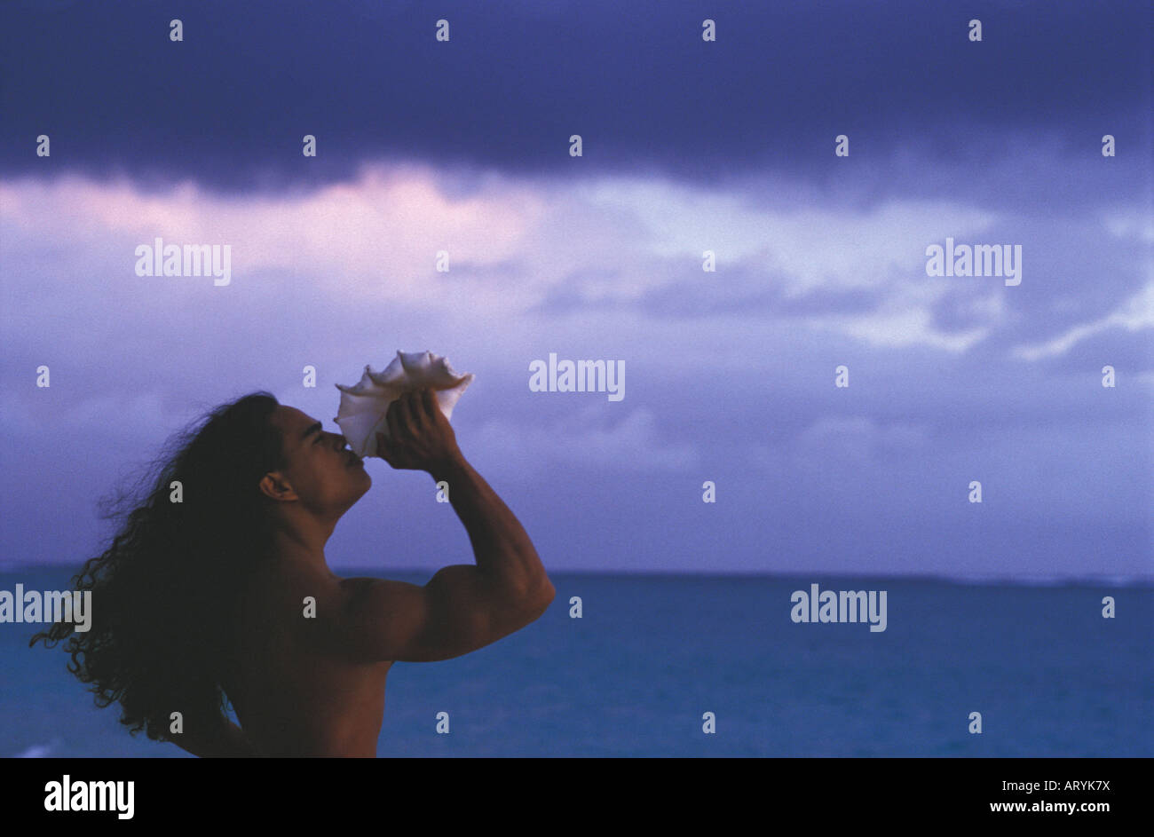 Young Hawaiian man blowing conch shell at sunrise Stock Photo Alamy