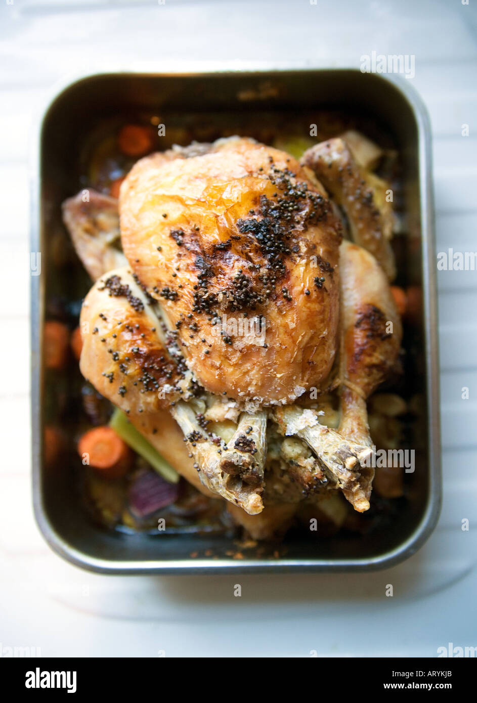 Organic roast chicken with vegetables in a roasting tray Stock Photo