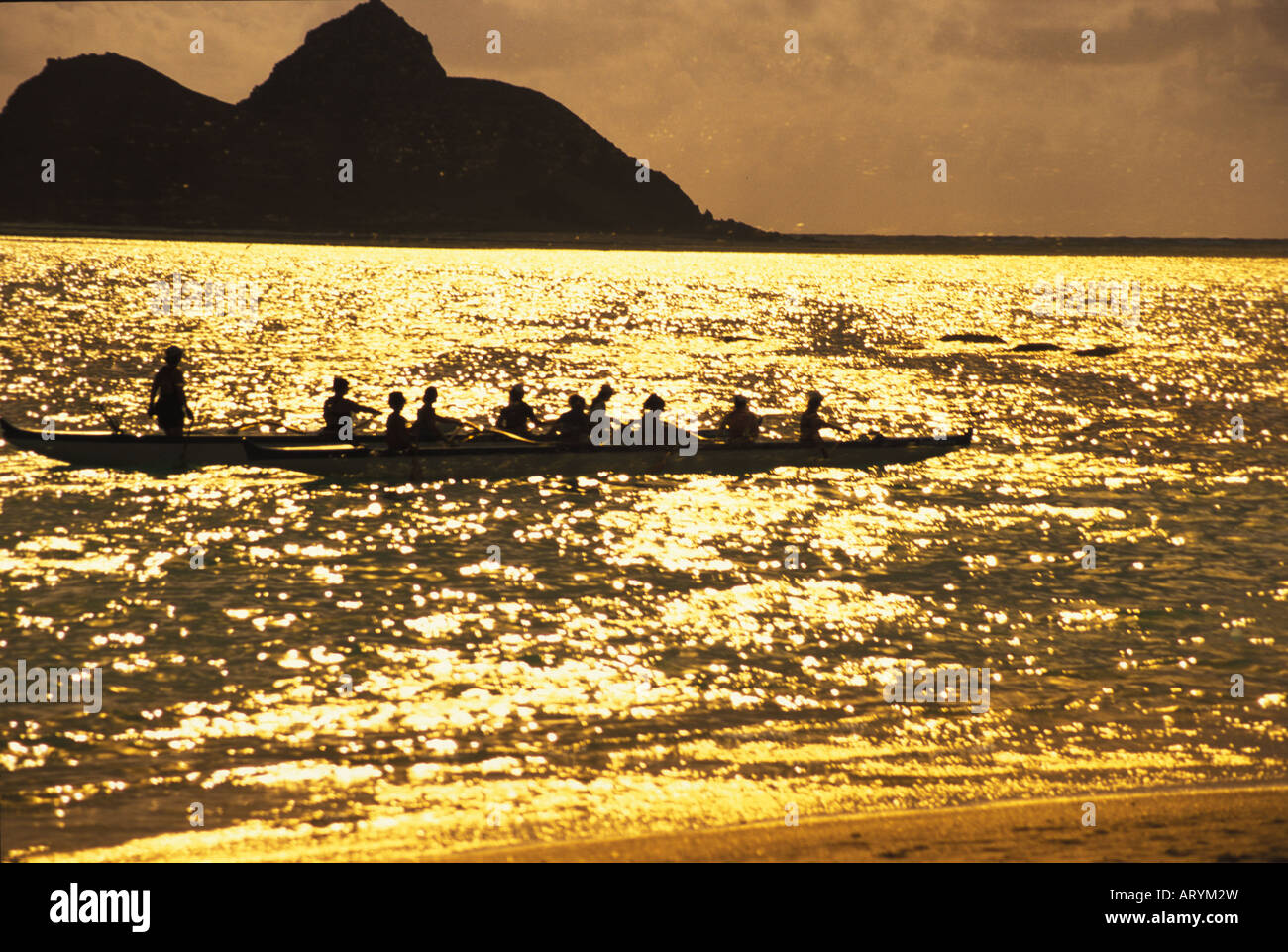 Outrigger canoe teams at sunrise, with the mokulua islands in rear