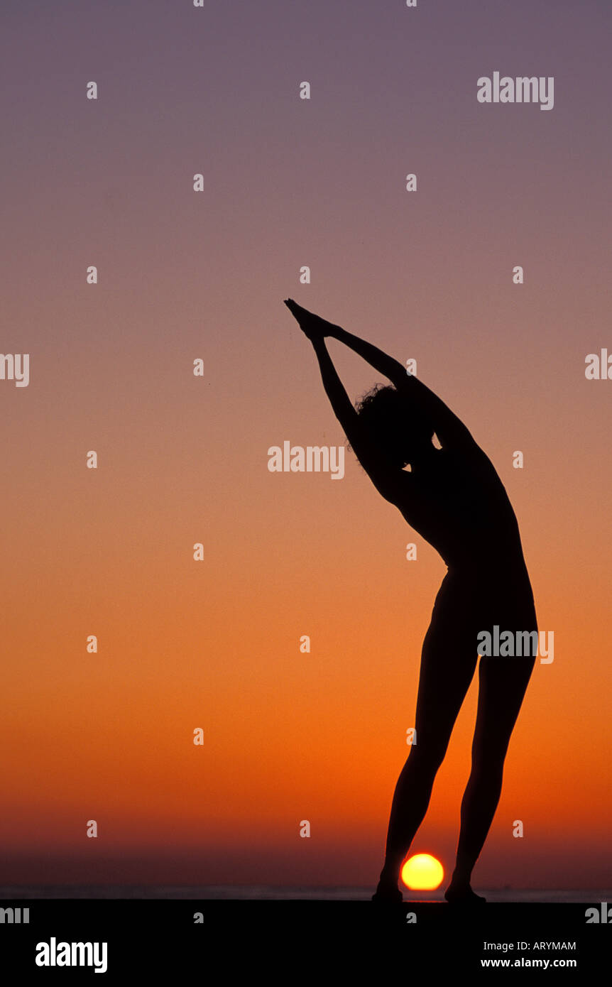 Yoga being performed on the beach at sunset Stock Photo