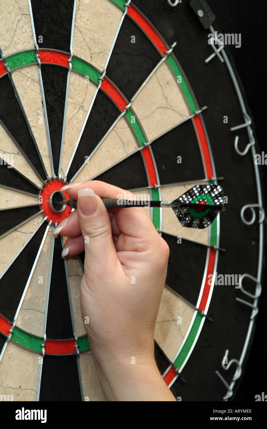 Womans hand takes dart from the bullseye on dartboard scoring fifity