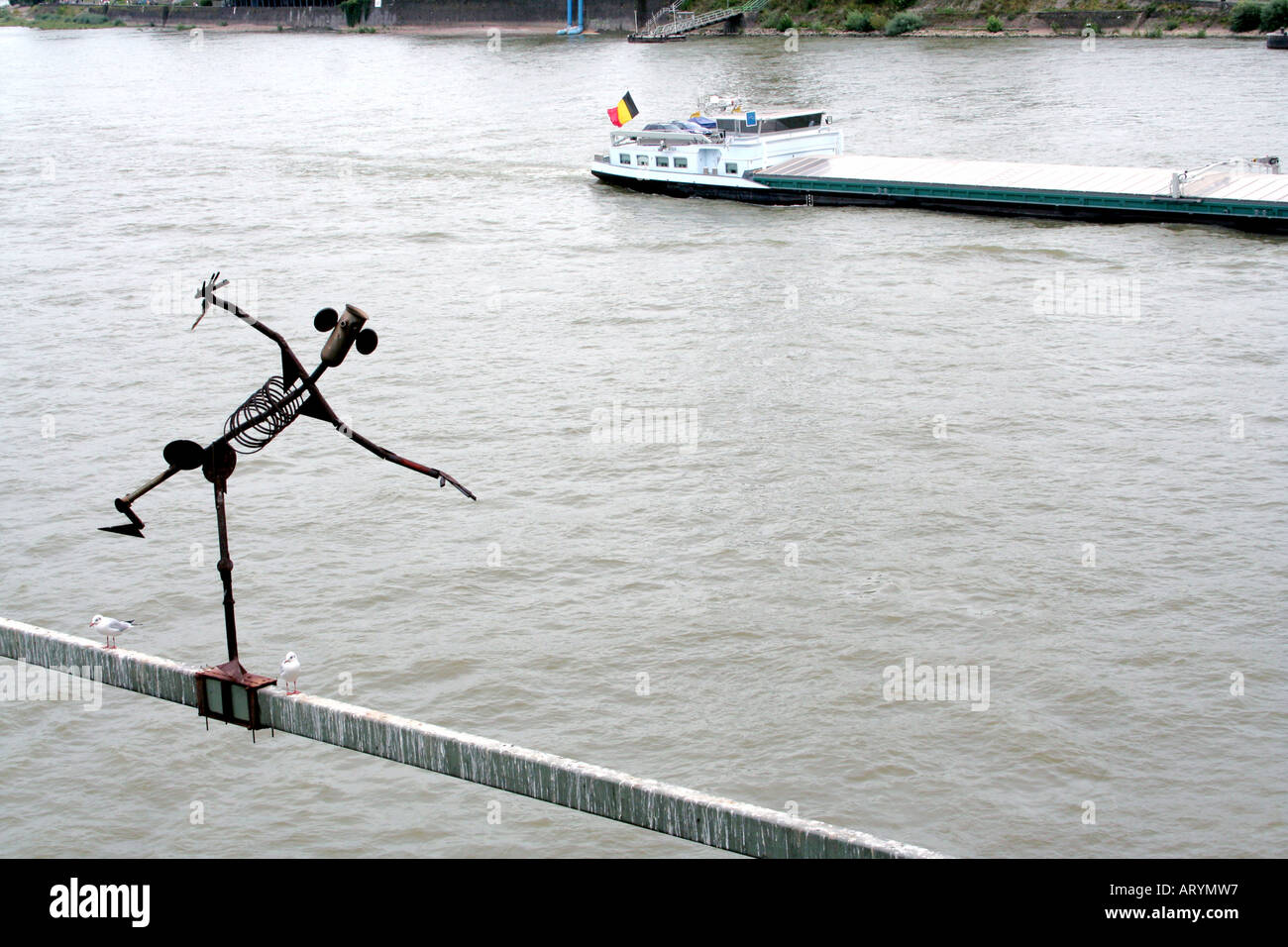 Iron Man steel sculpture of a little man and barge Hohenzollern Bridge Cologne North Rhine Westphalia Germany Stock Photo