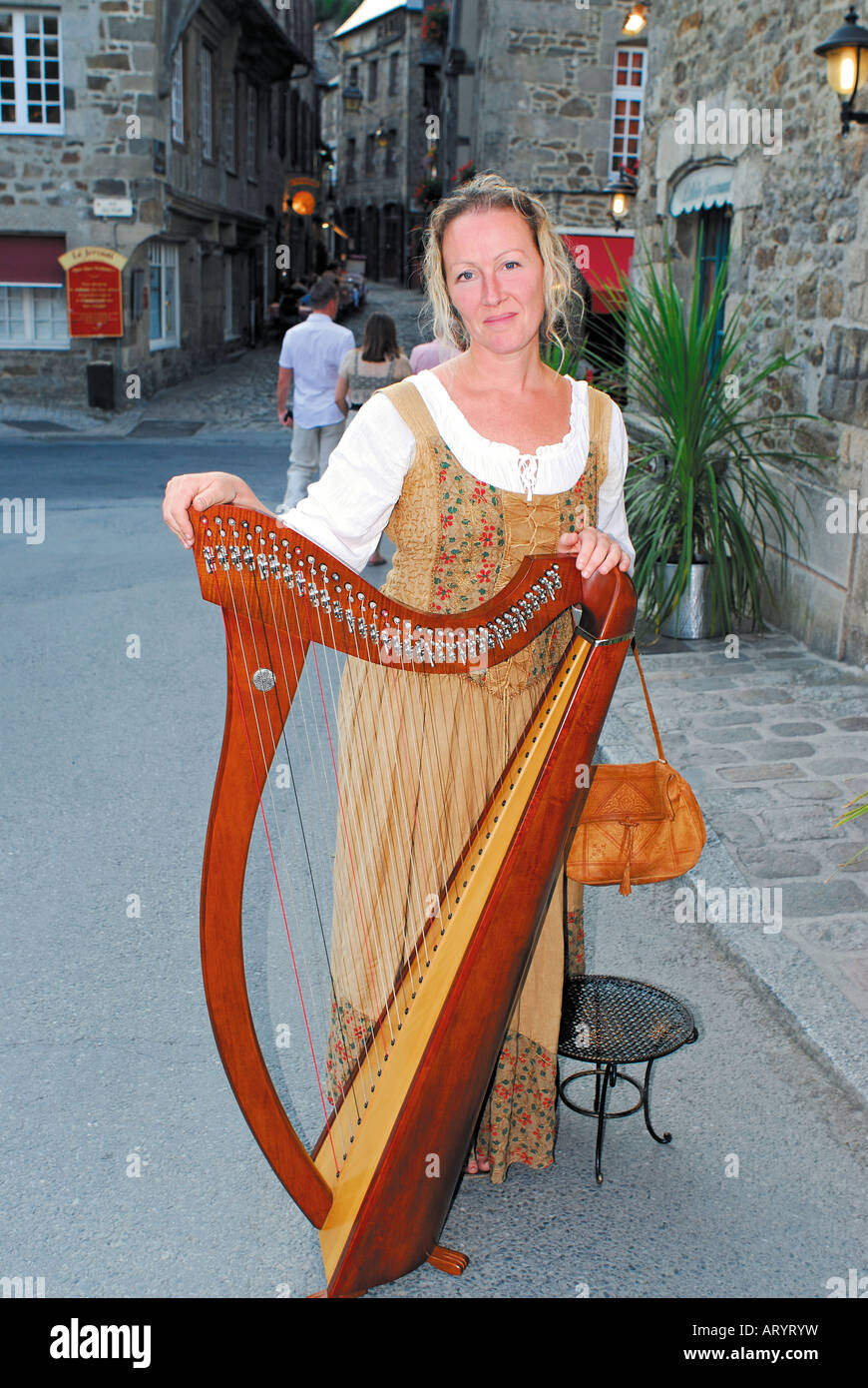 Musician Lydwen with traditional celtic harp in the historic riverside from Dinan, Brittany, France Stock Photo