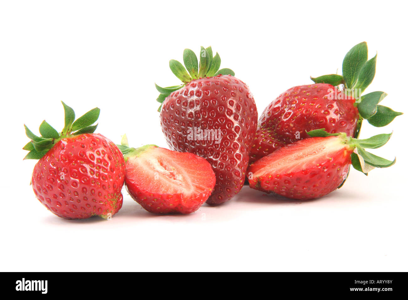 group of strawberries close up one is cut in half isolated on white background healthy eating Stock Photo