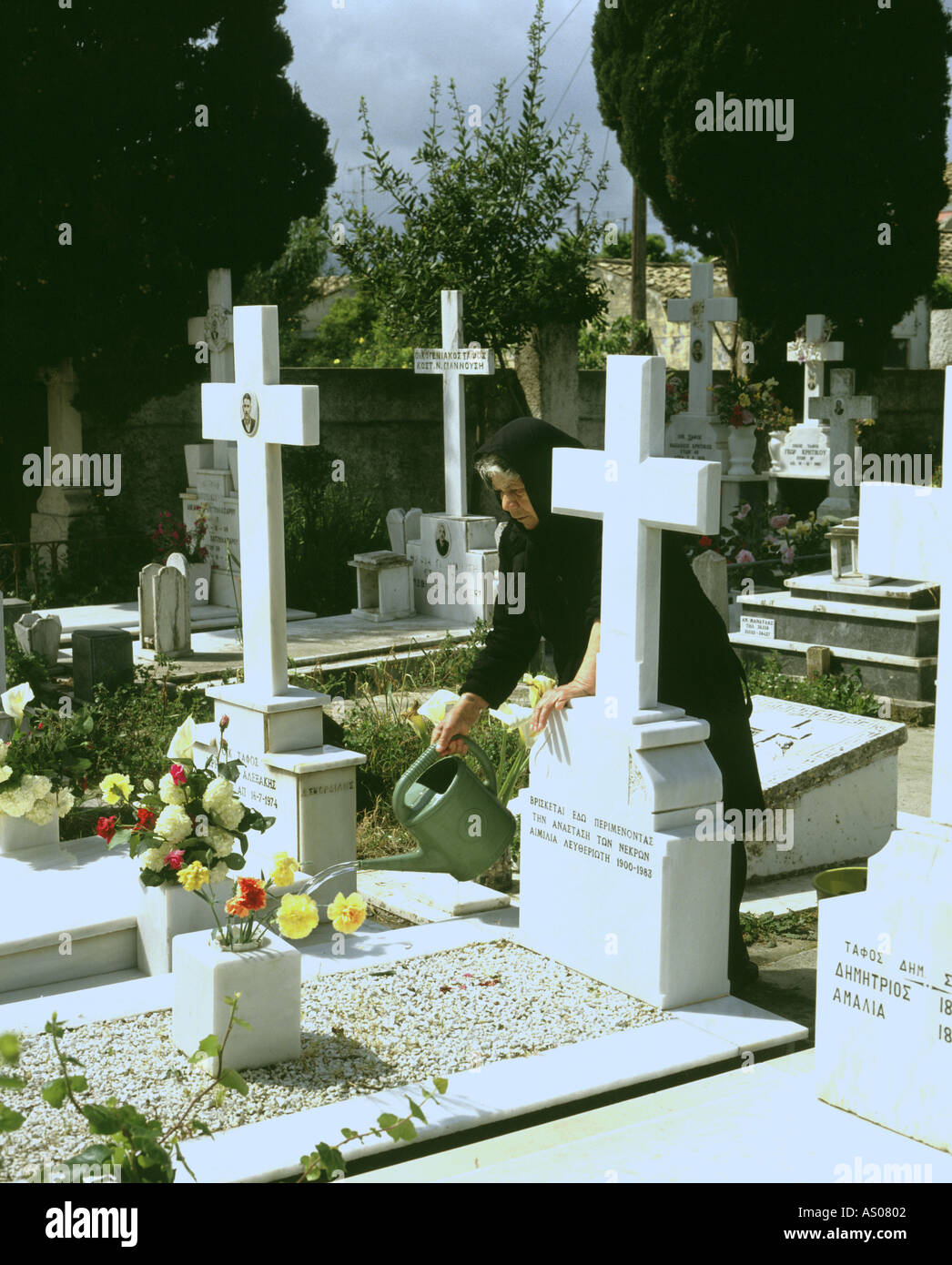 Corfu woman tending grave in cemetery Stock Photo
