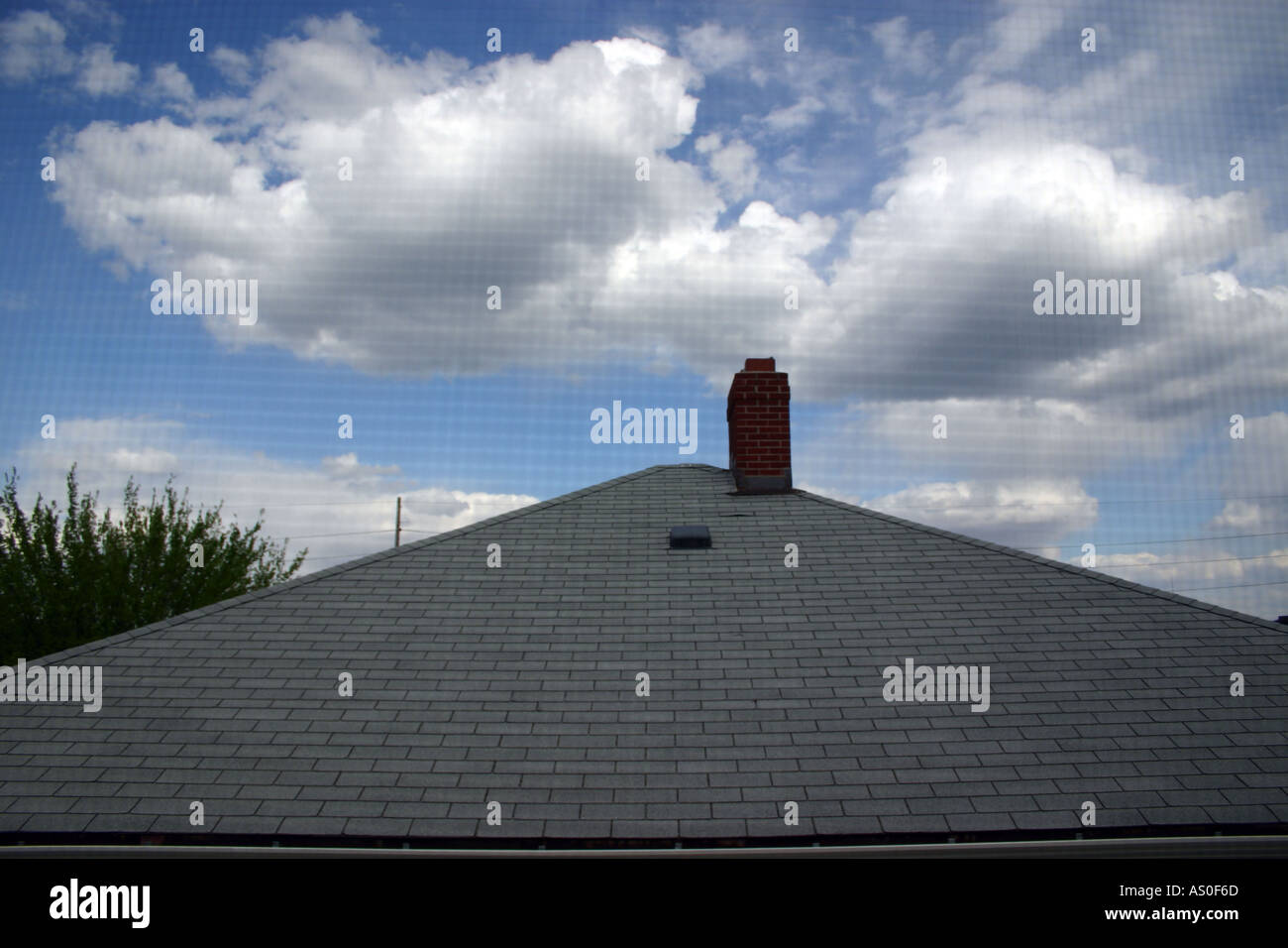 view of roof and cloudy blue sky through the screen in window rooftop roof top Stock Photo