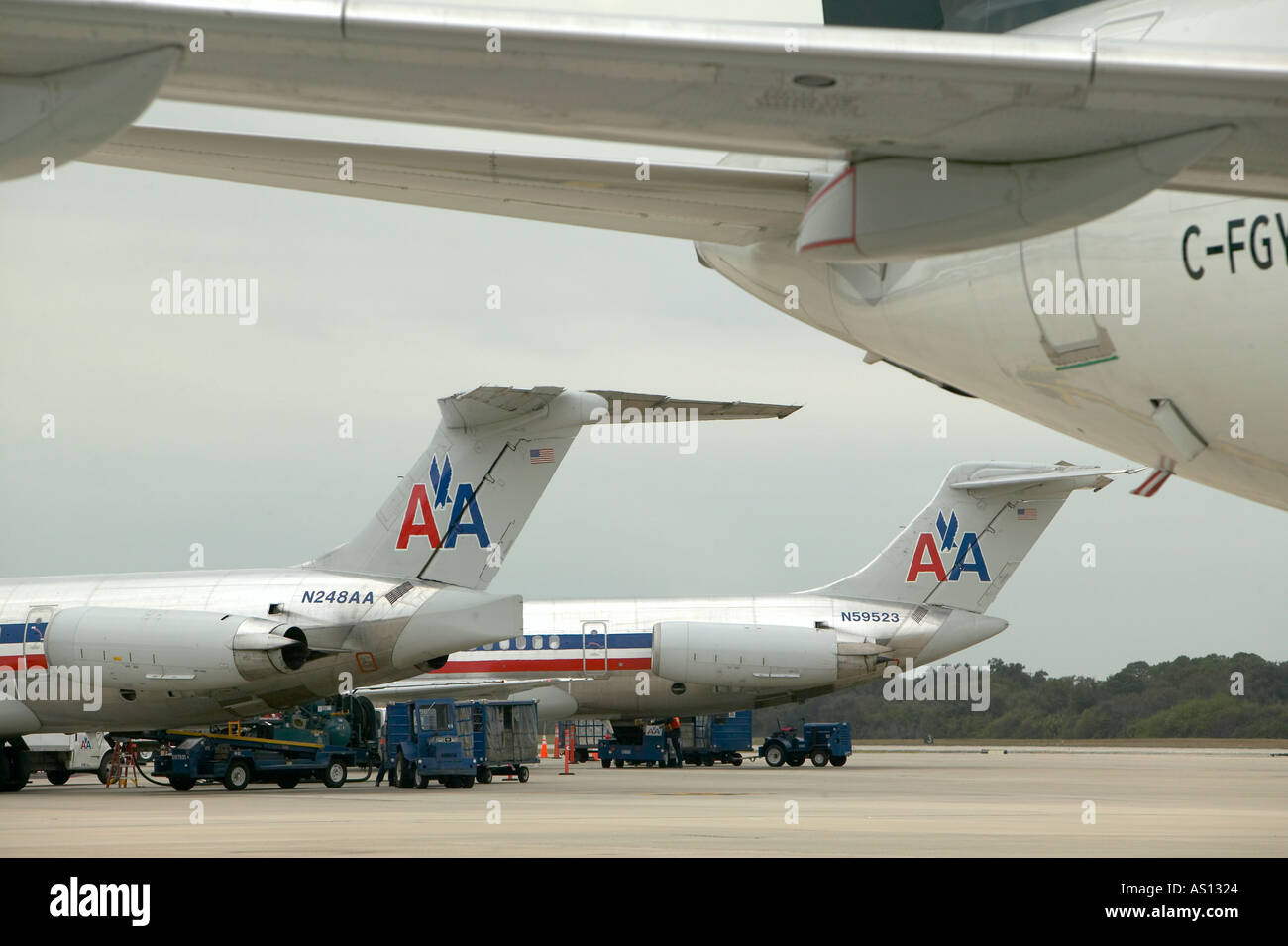 American Airlines passenger airplanes waiting at terminal with baggage being unloaded on a