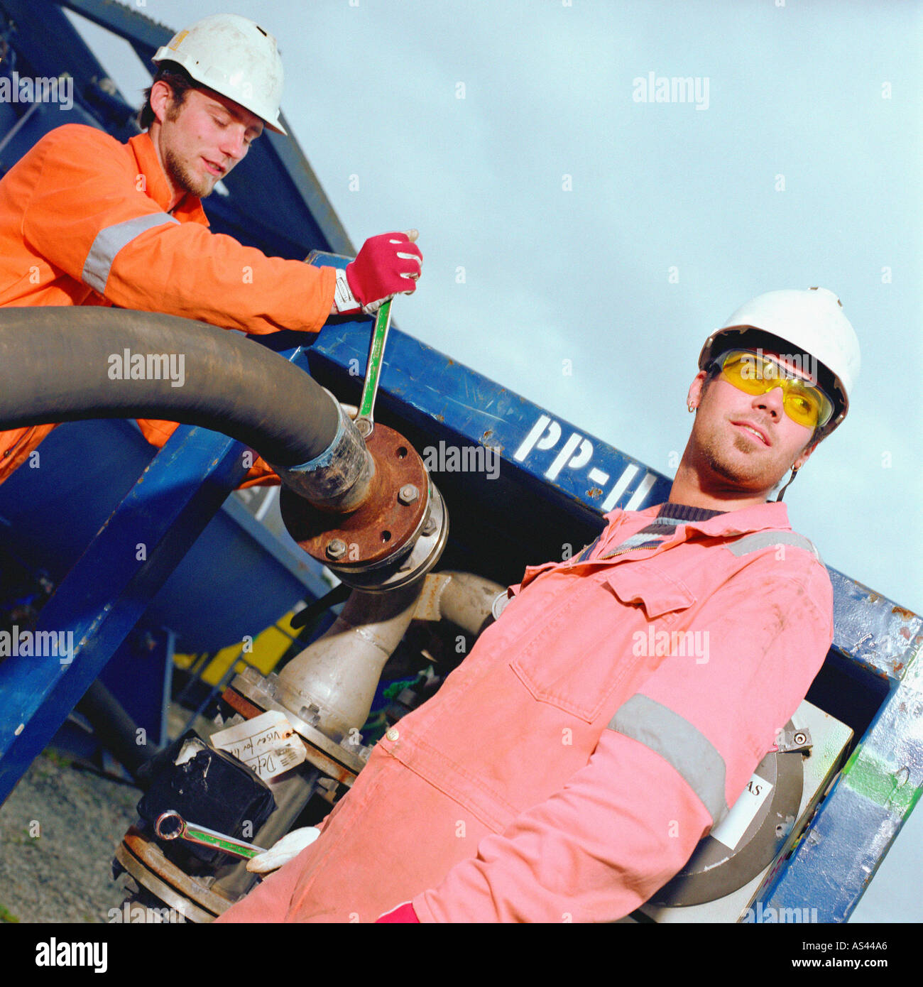 Construction workers adjusting pipe Stock Photo