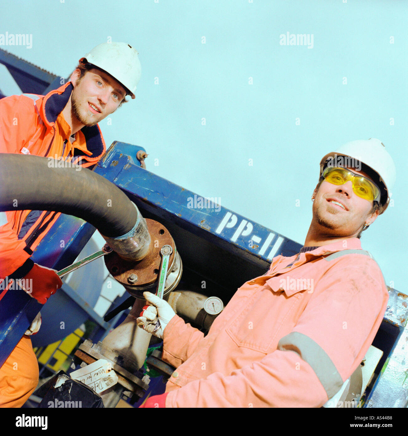 Construction workers adjusting pipe Stock Photo