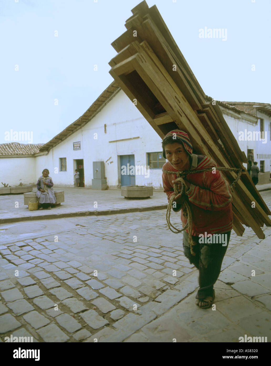 An indian man in Cuzco Peru making a delivery of wooden products carried on his back Stock Photo