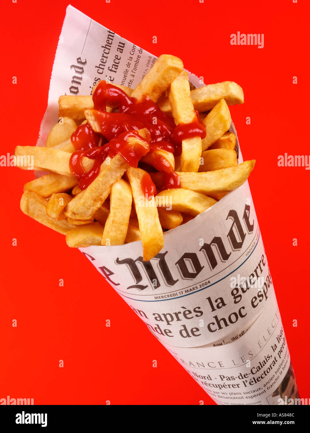 CHIPS FRIES IN FRENCH NEWSPAPER WITH TOMATO KETCHUP Stock Photo