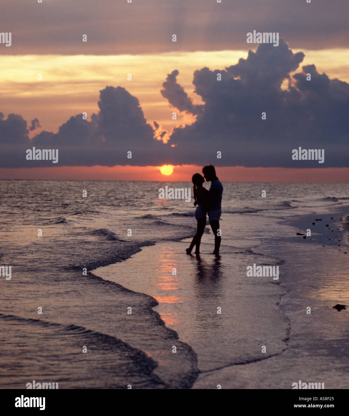 couple embrace on beach at sunset Stock Photo