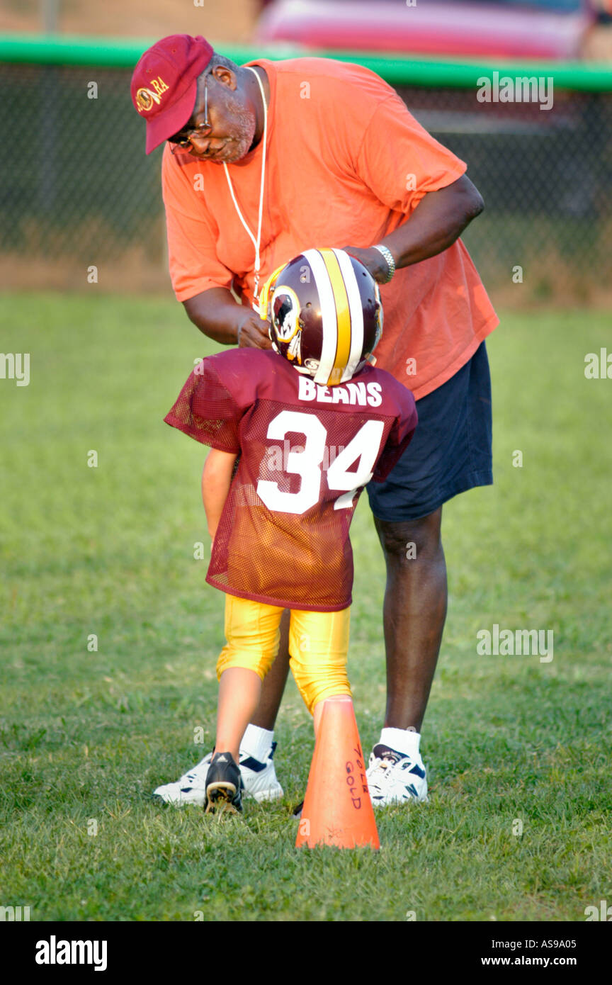 Senior black coach teaching real young football players how to play