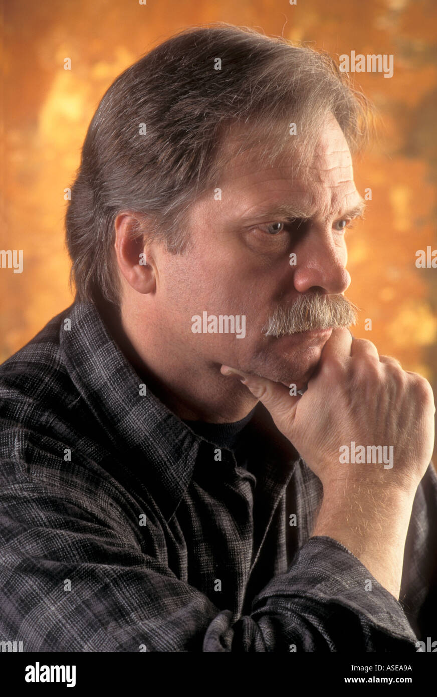 a man in deep thought rests his chin in his hand Stock Photo