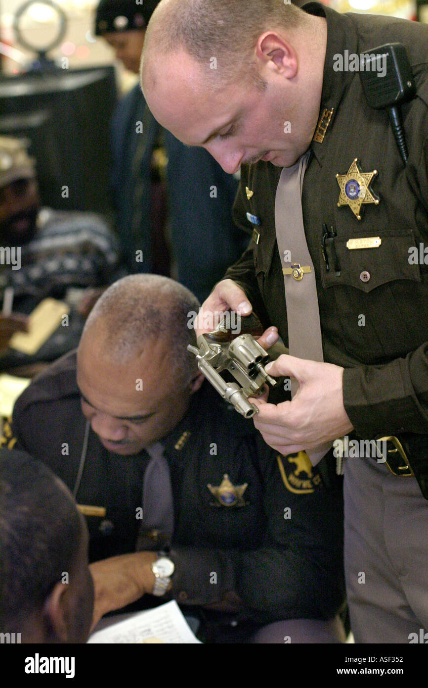Sheriff s deputy examines handgun turned in in a cash for guns swap Stock Photo