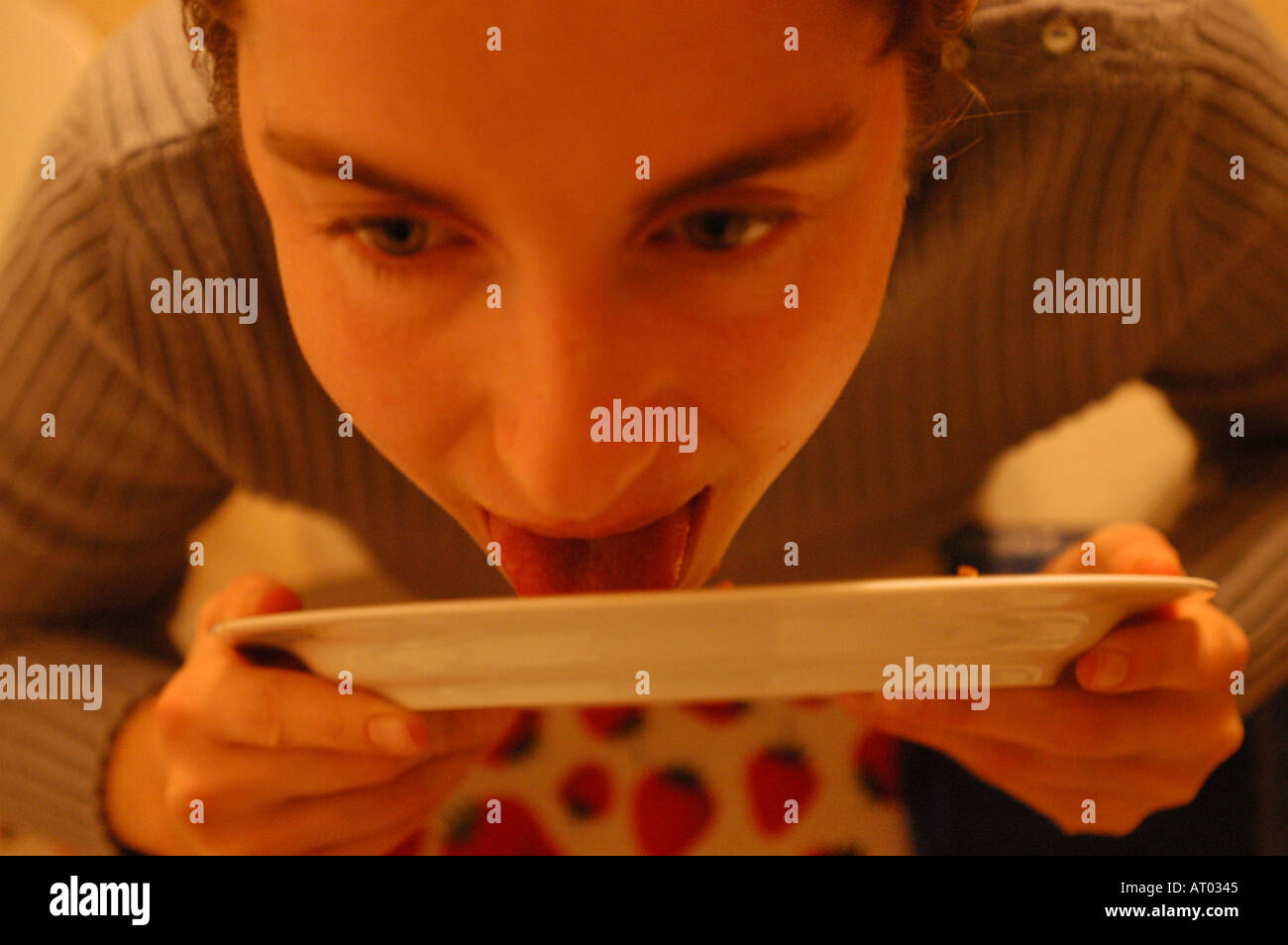 Young woman licking plate Stock Photo Alamy