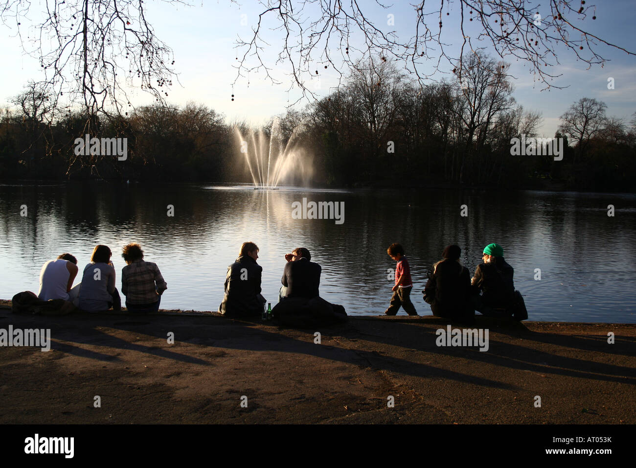 Group of young people sitting beside park lake and fountain Stock Photo ...