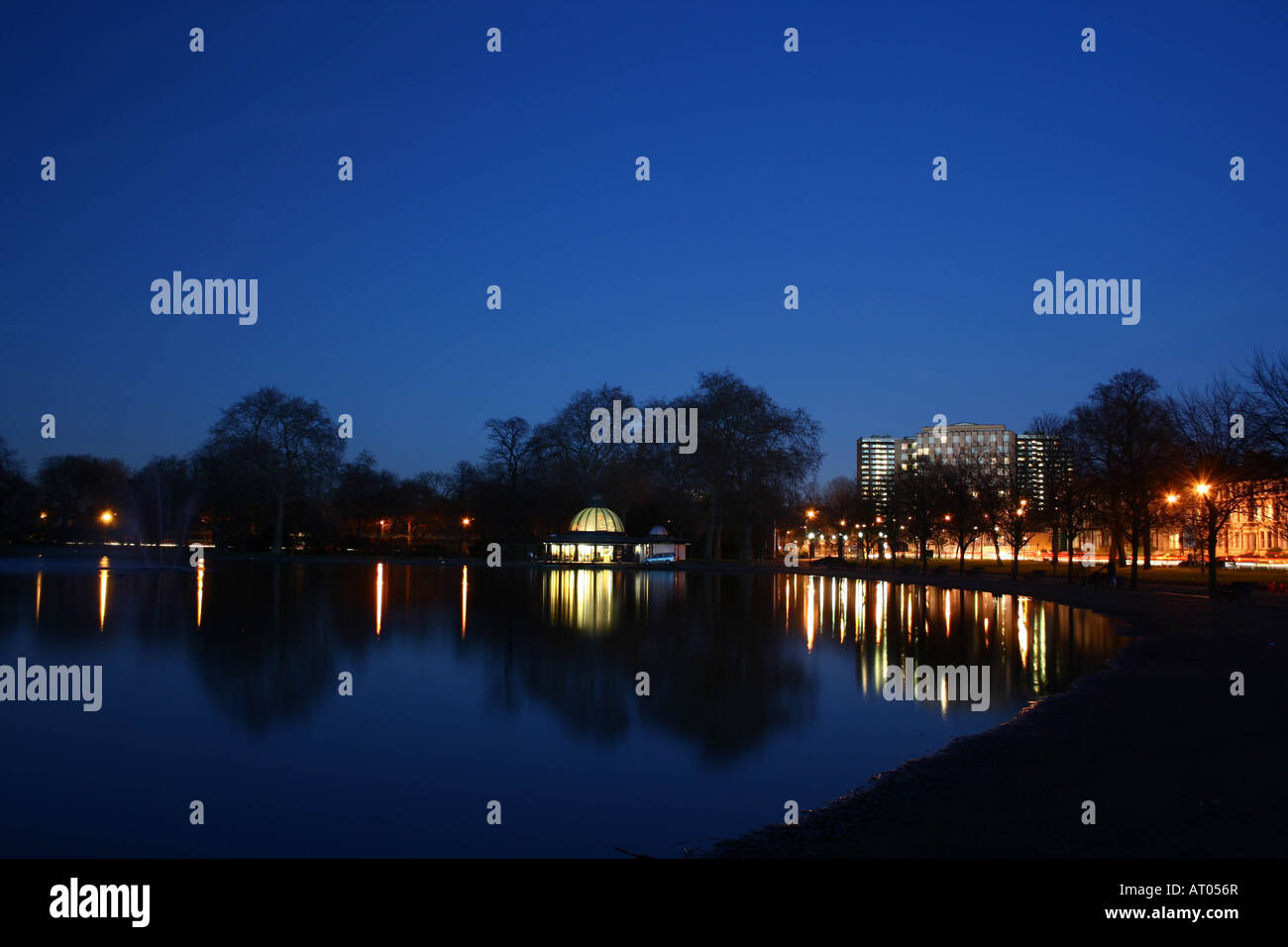 Park lake and cafe at twilight with clear sky and reflections of lights in water Stock Photo