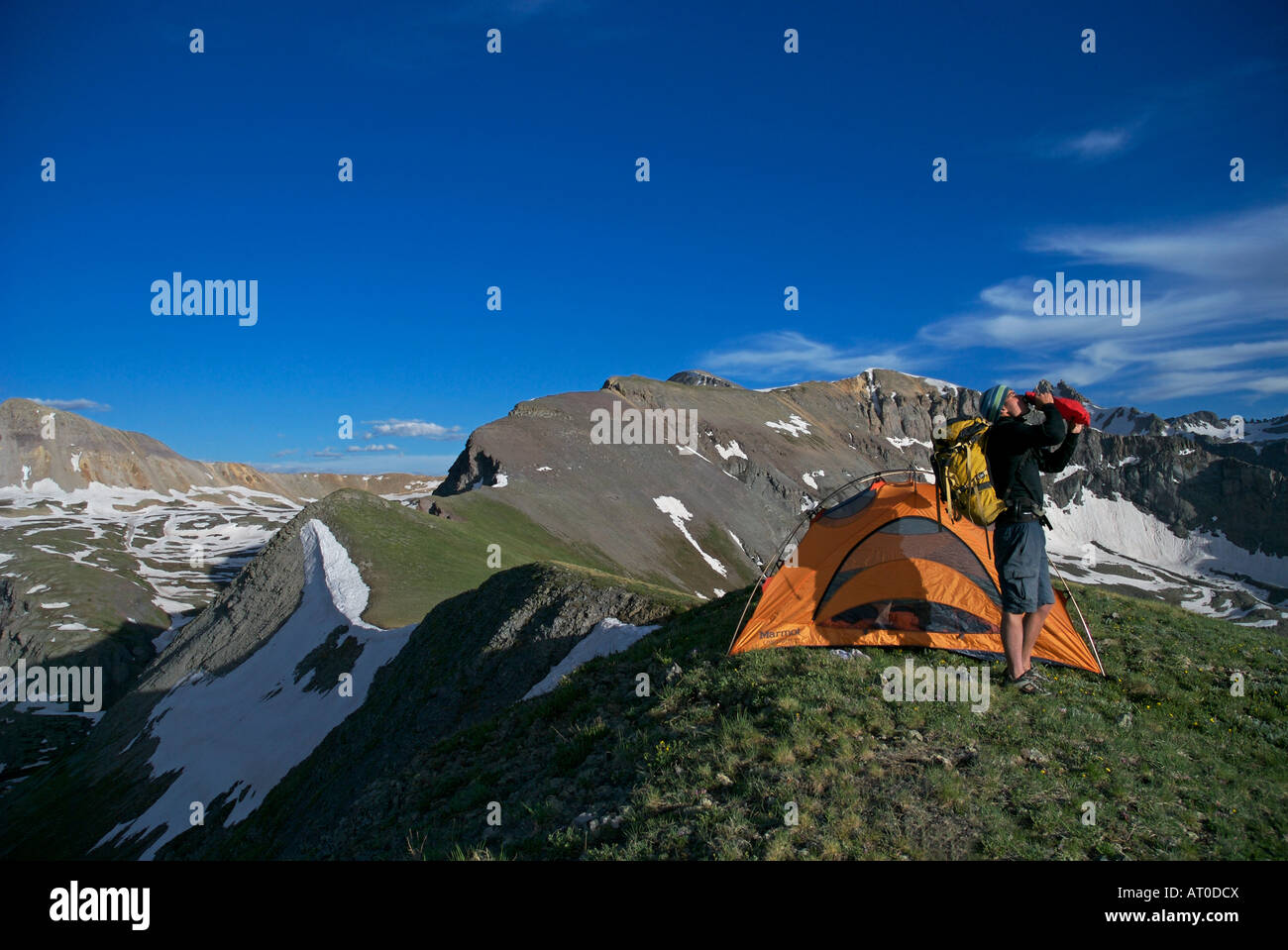 A man take a drink of water before departing his camp high up on a ridge in the San Juan mountains near Telluride Colorado Stock Photo