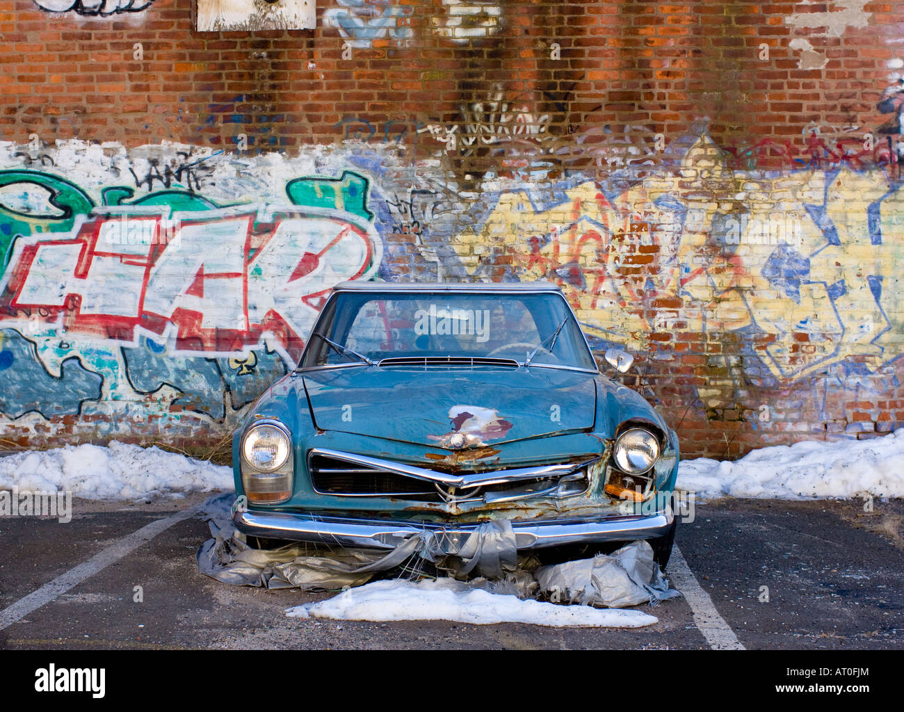 An old abandoned car with graffiti on a wall. Urban Street scene in New
