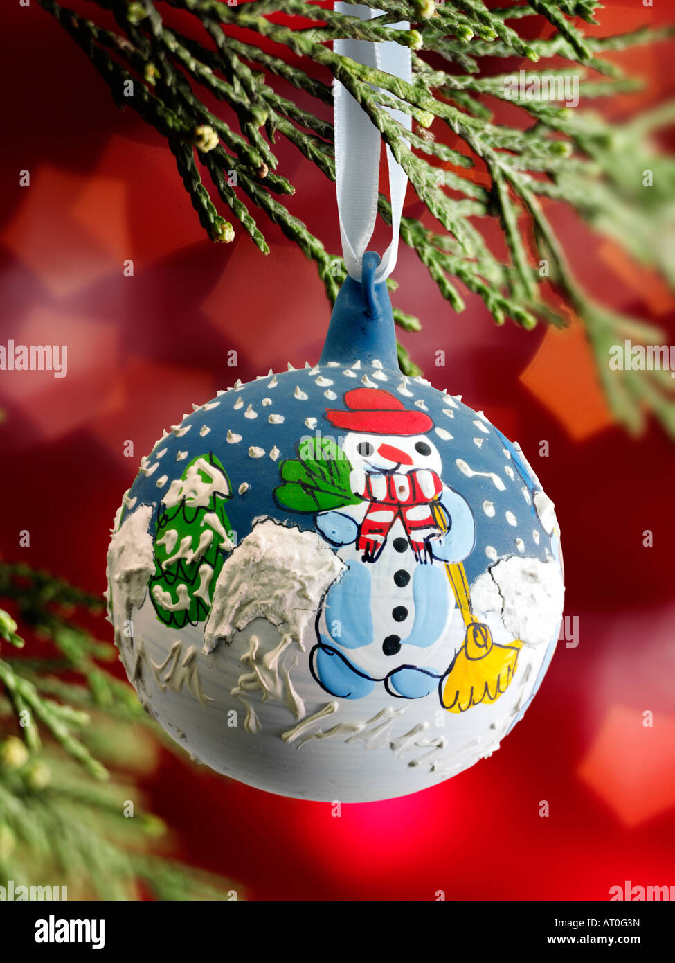 traditional  festive decorated Christmas snowman bauble hanging on a Christmas tree with lights behind Stock Photo
