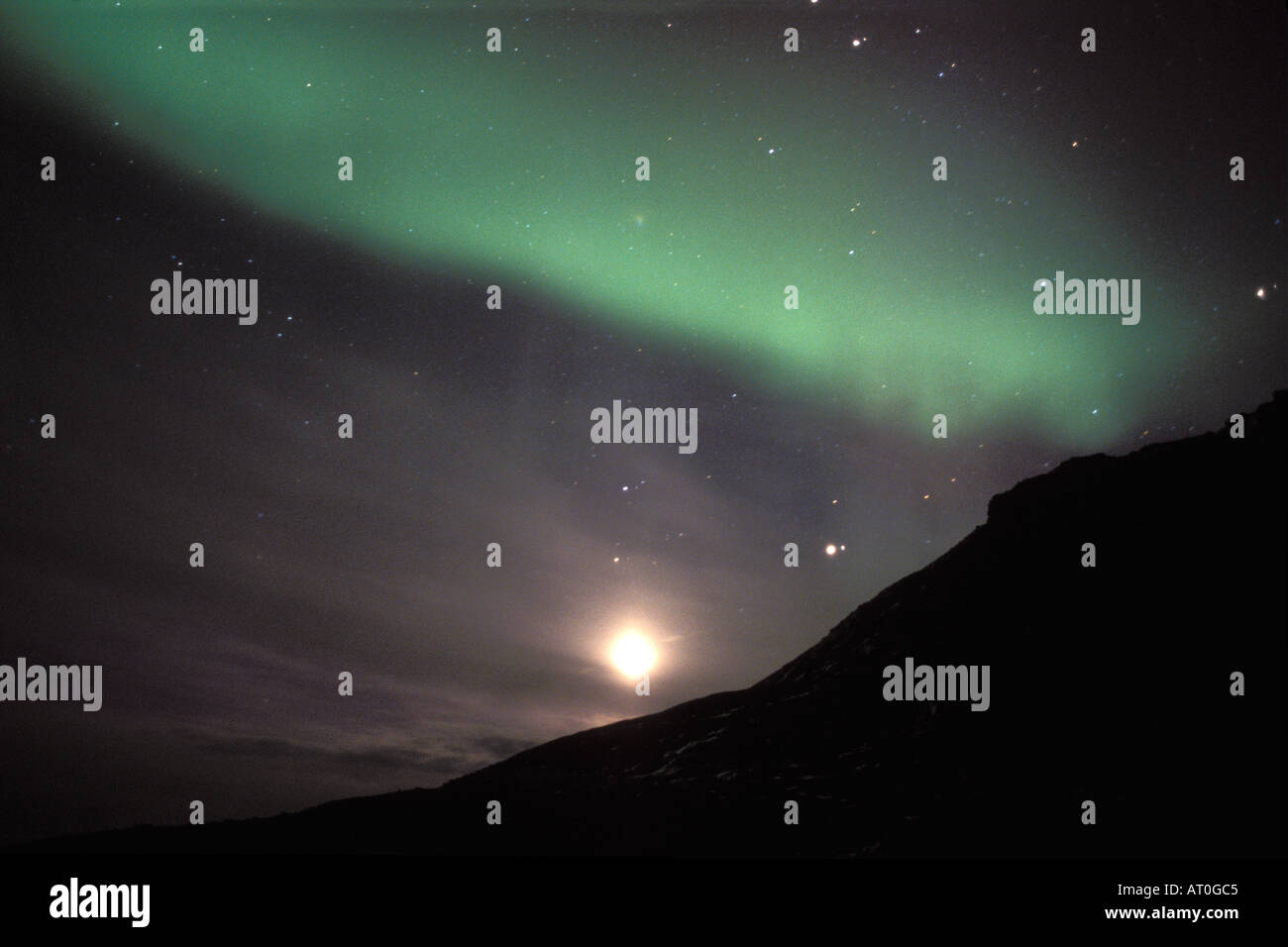 northern lights Aurora borealis and full moon over the foothills of the