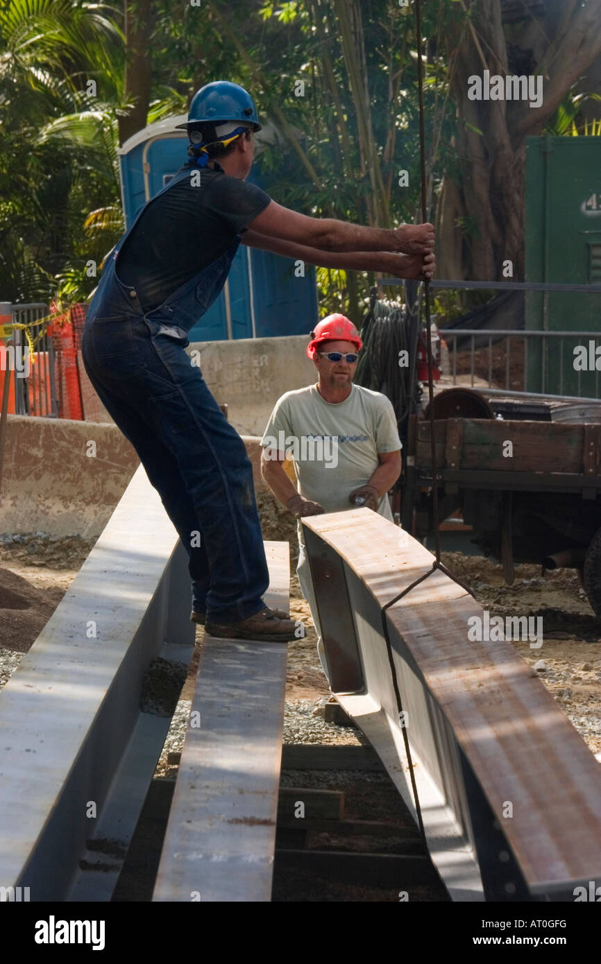 Two laborers in hard hats moving steel beams into position at a building site. Stock Photo