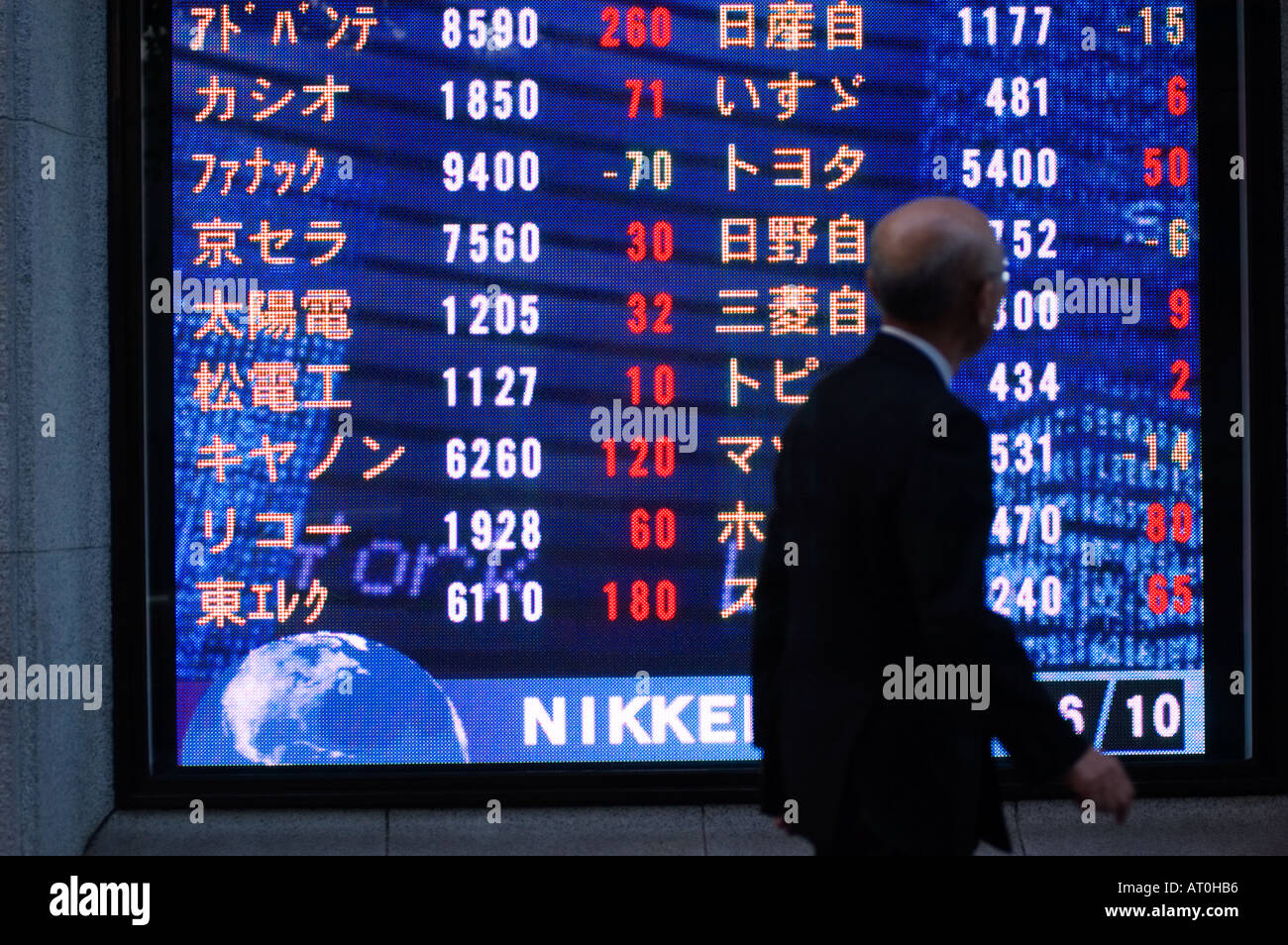 Man walks past stock market index board on Tokyo Street Japan Stock Photo