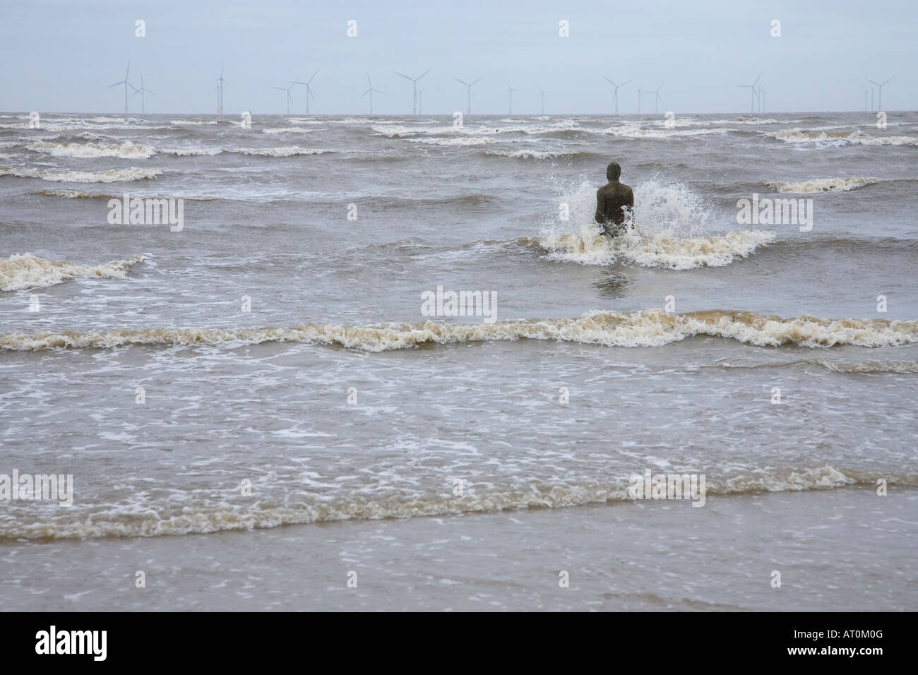Antony Gormley sculpture of man looking out to sea towards wind power