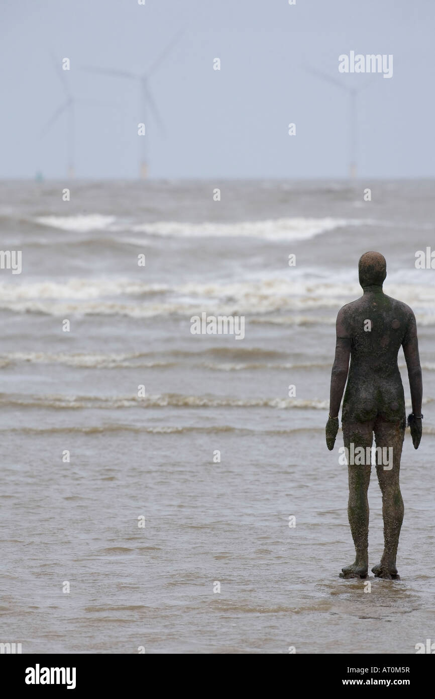 Antony Gormley sculpture of man looking out to sea towards wind power