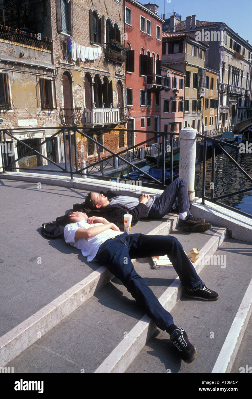 Two exhausted tourists rest on a bridge in the Cannaregio district of Venice. Stock Photo