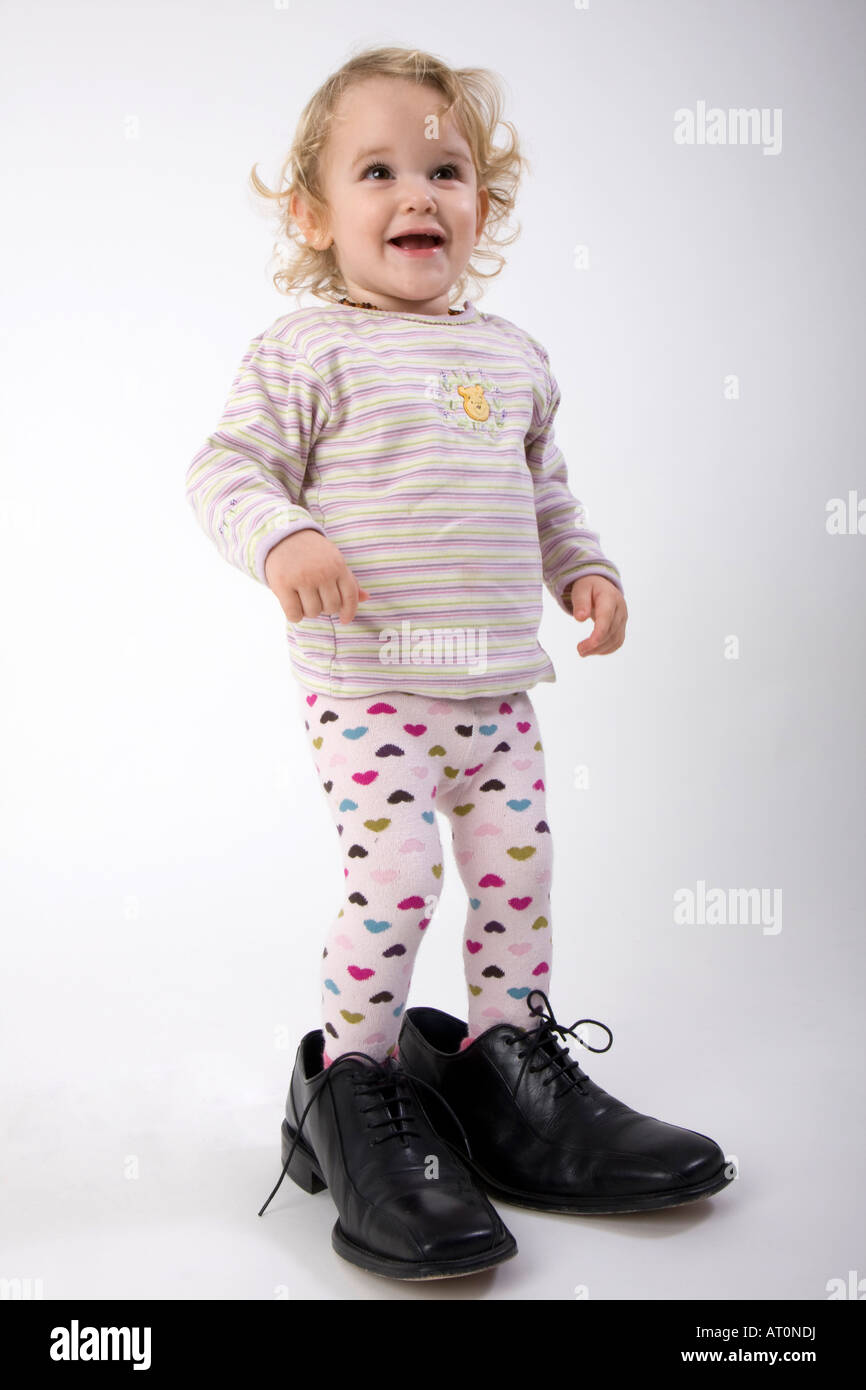little girl in far too big black shoes Stock Photo