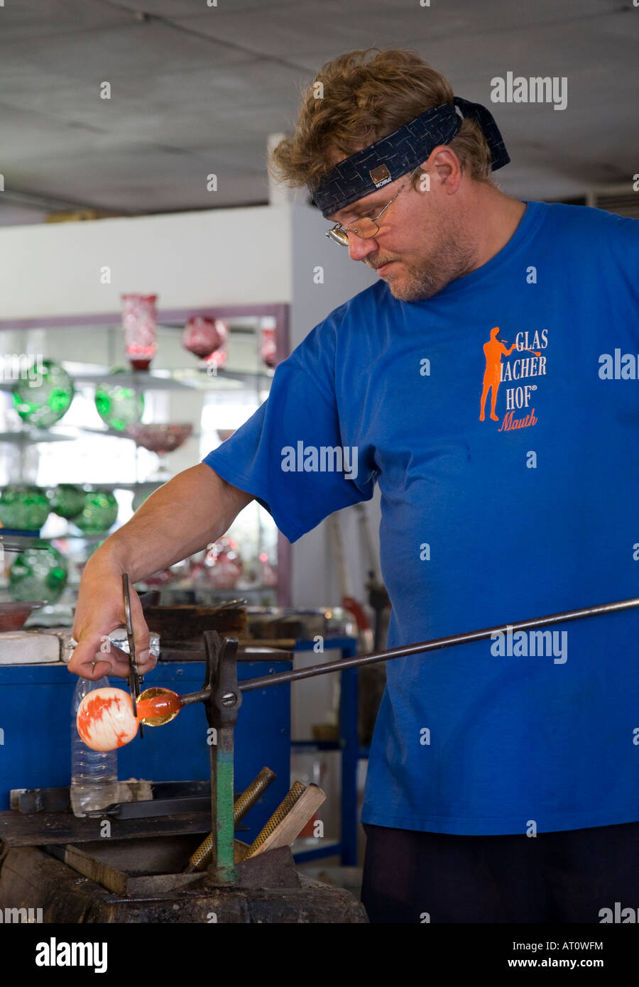 Man finishing glassblowing by shaping hot glass Mauth Bavaria Germany