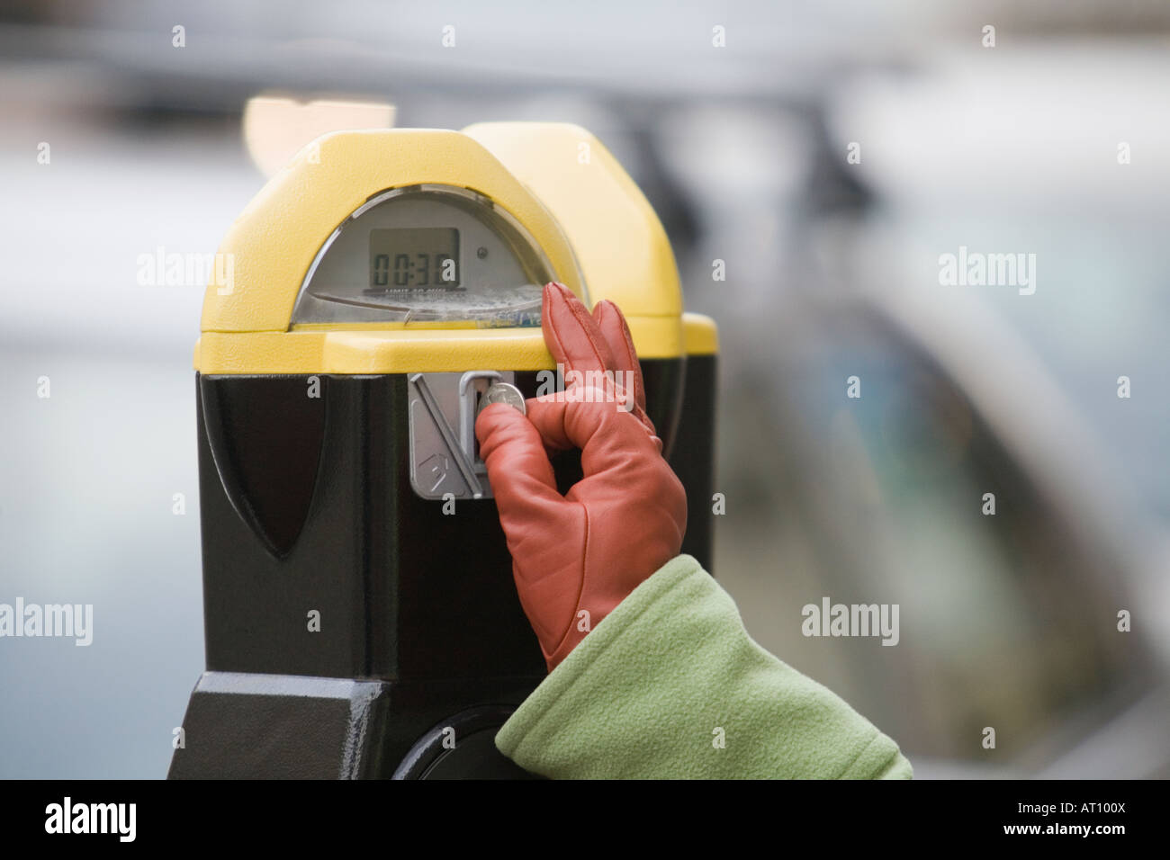 Closeup of a person's hand inserting a coin into a parking meter Stock