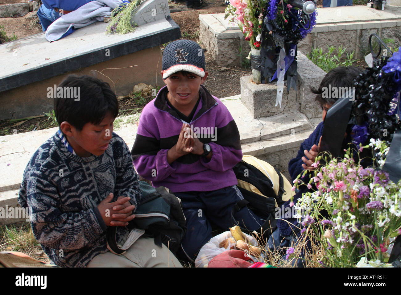 Children praying in front of a grave at the cemetery in Llallagua, Bolivia Stock Photo