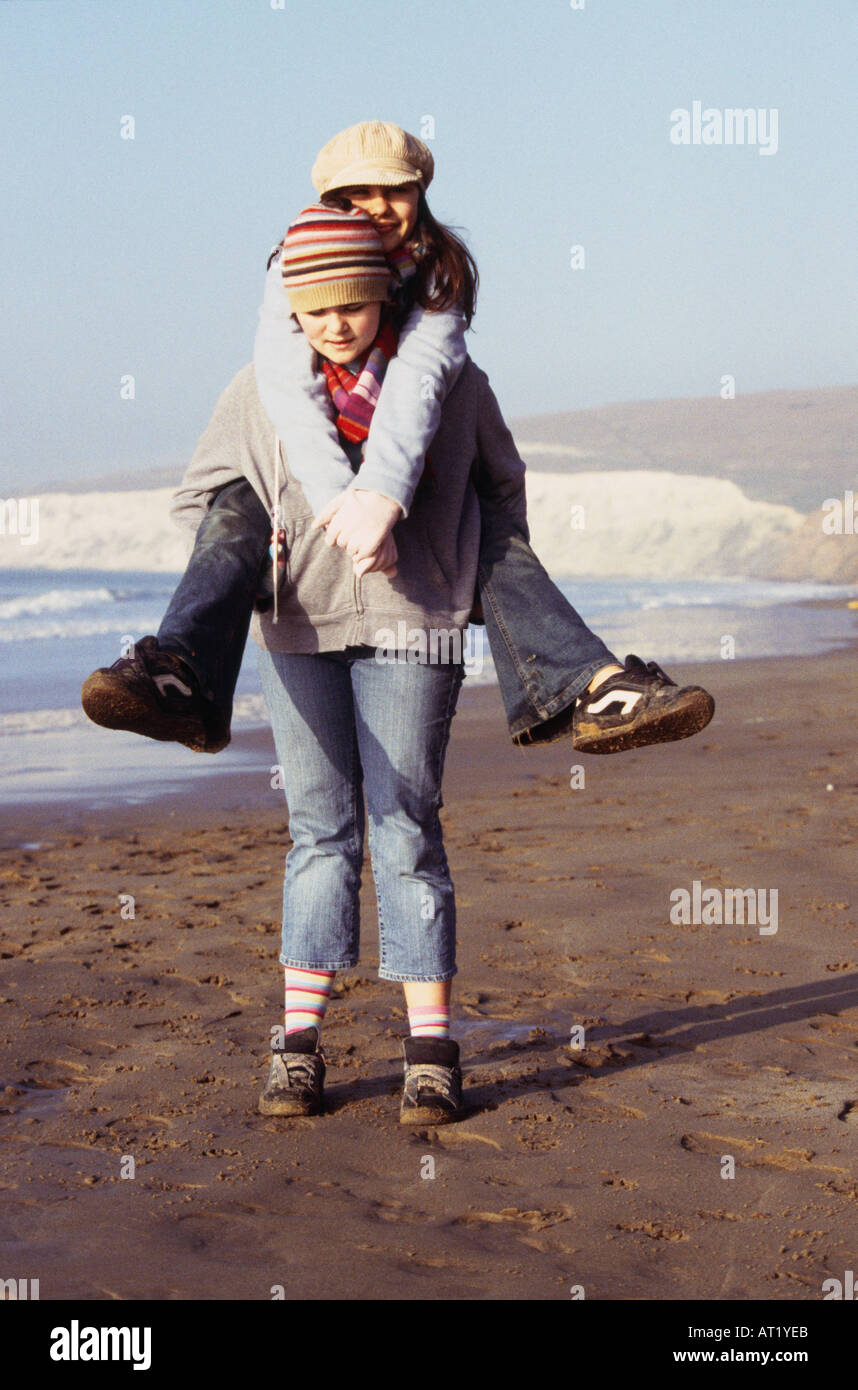 A girl giving a piggy back to her friend Stock Photo