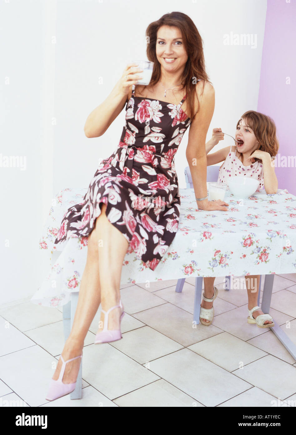 A woman sitting on a table drinking a glass of milk Stock Photo