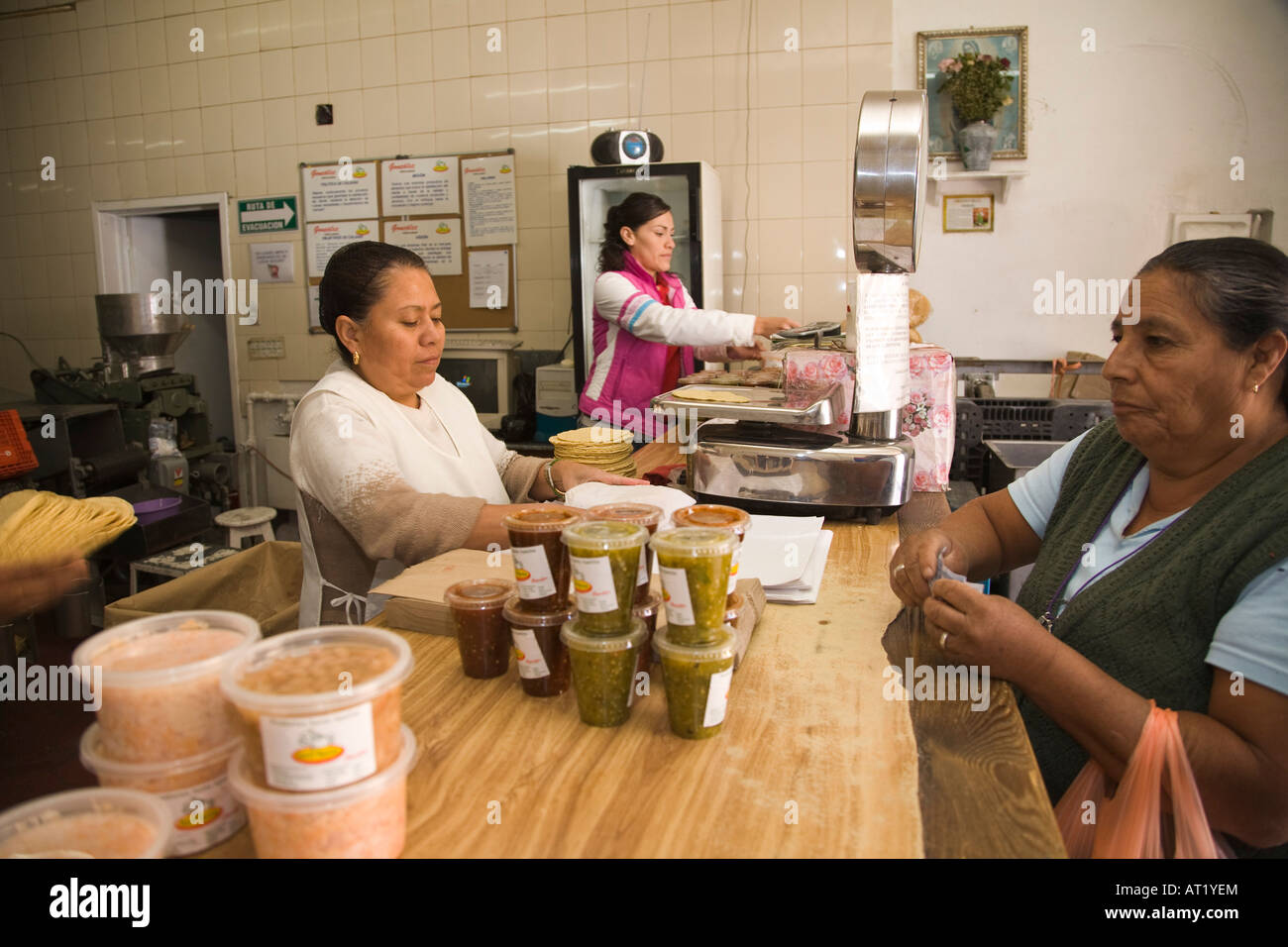 MEXICO Guanajuato Woman wrap stack of tortillas for adult female customer scale and salsas in small tortilla making shop Stock Photo