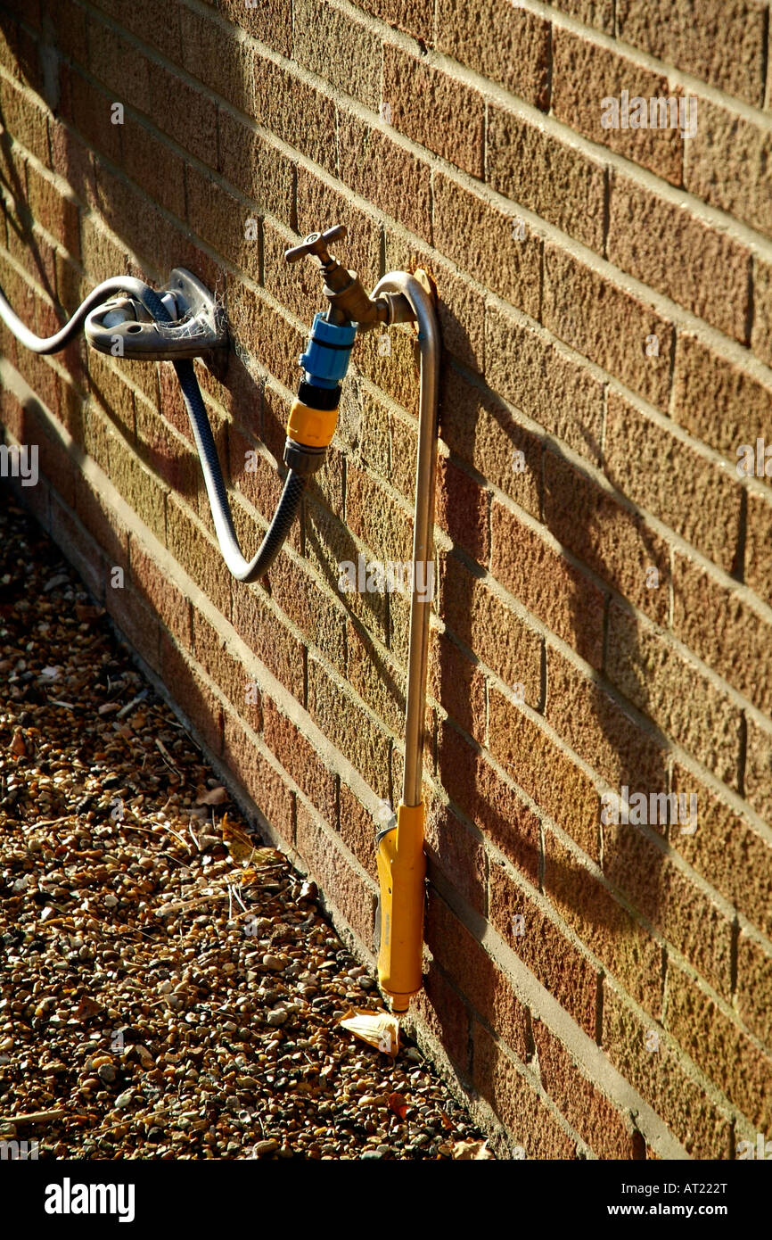 outside water tap with garden hose and back flow restrictor valve attached Stock Photo Alamy