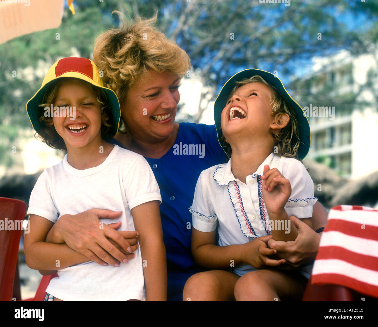 Mother and two daughters sitting outside and laughing together on family holiday in sunny situation Kodak moment Stock Photo