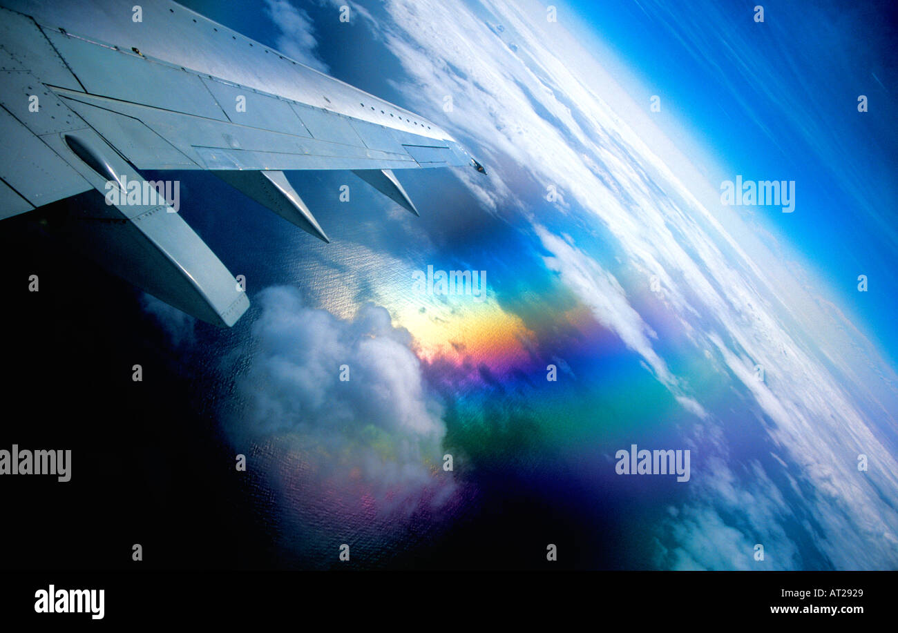 Airplane window view with clouds and polarised polarized reflection of sun shining on wing and sea Stock Photo