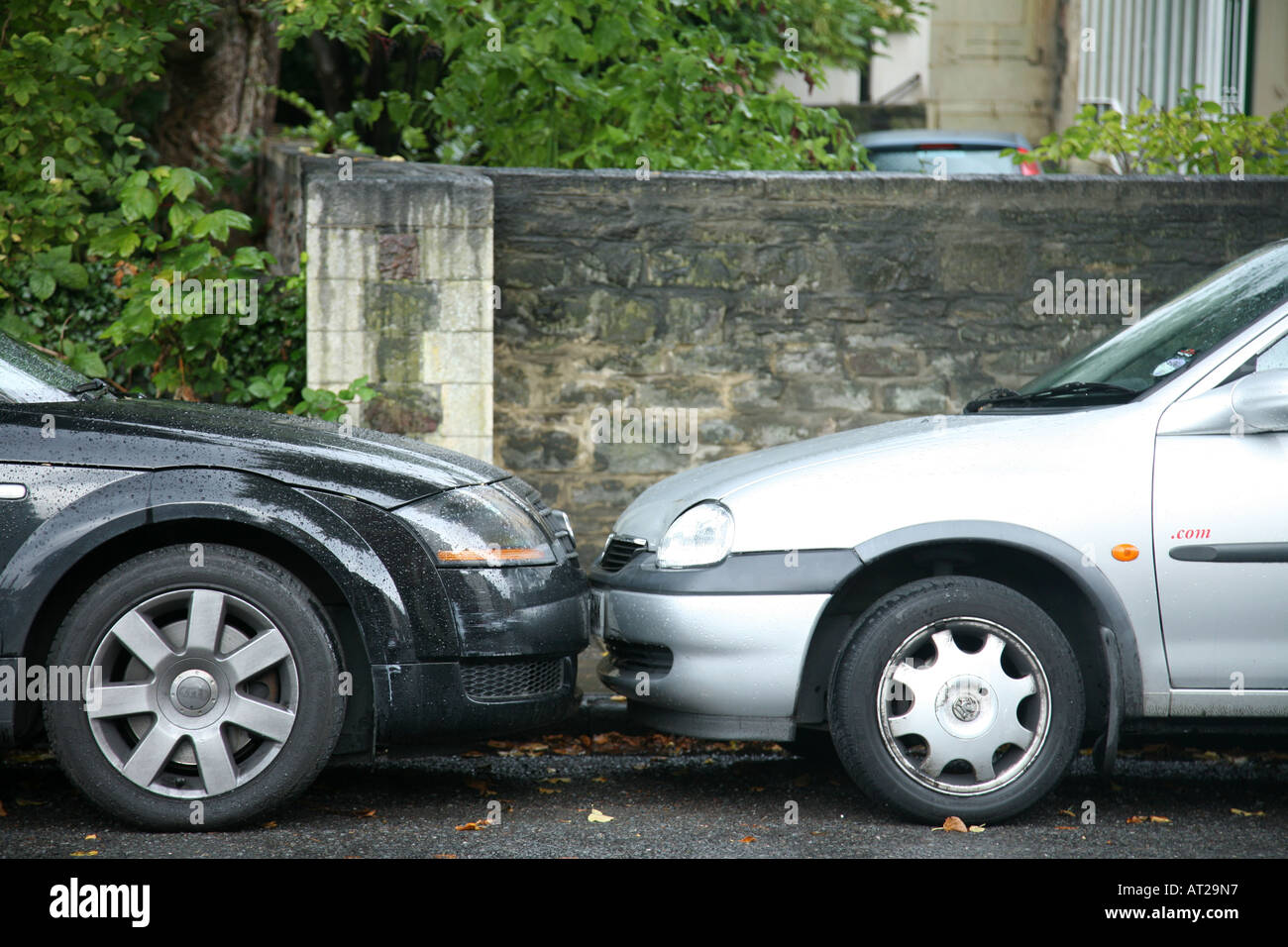 Two very badly parked cars whos bumpers are actually touching This is a landscape shot Stock Photo