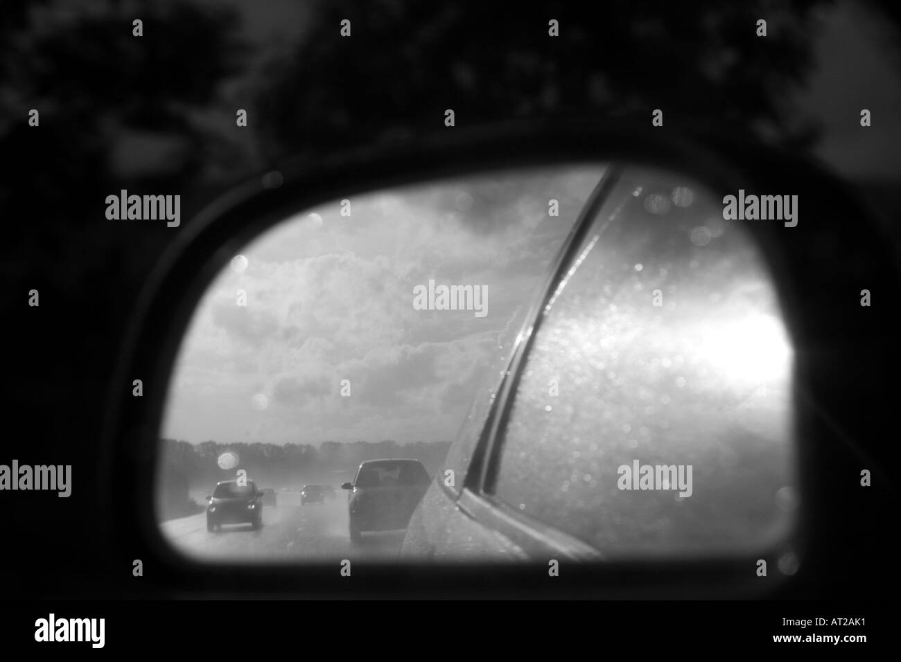 A stormy looking M4 motorway is reflected in a car s reaviewmirror This image is black and white Stock Photo