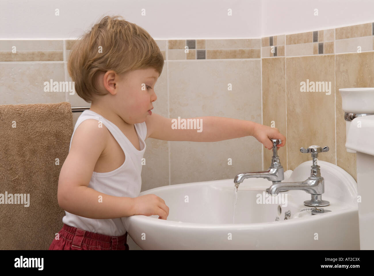 boy toddler using taps at sink in bathroom Stock Photo Alamy